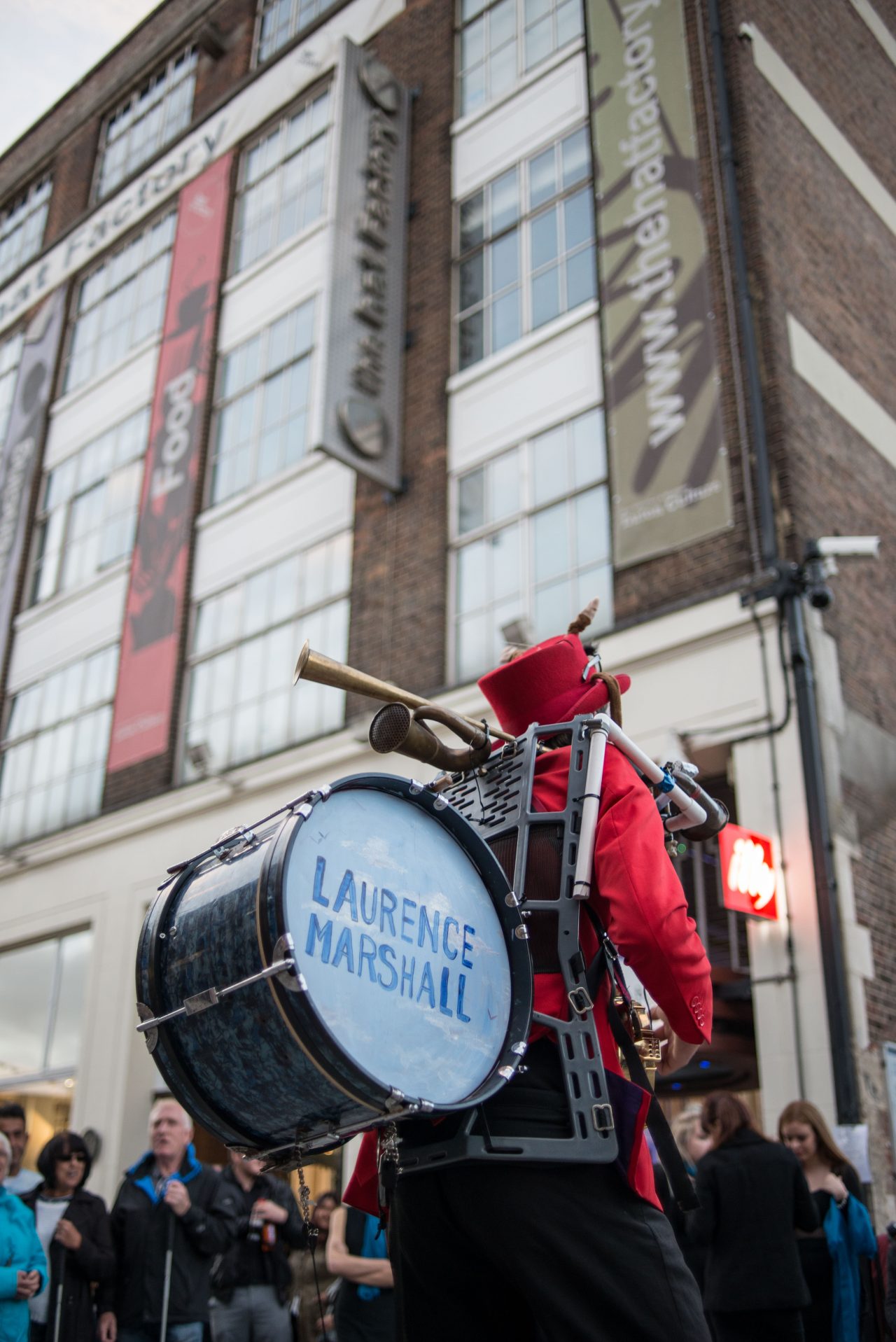 Laurence Marshall, the one man band, shot from the back with his name printed on the drum in blue paint launching the public realm arts project.