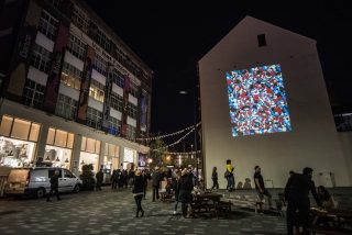 Vibrant artwork projected onto the Culture Wall stating 'Hand Must Mind Must Work.'